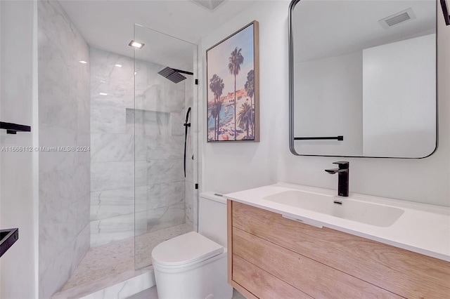 bathroom featuring vanity, toilet, and tiled shower