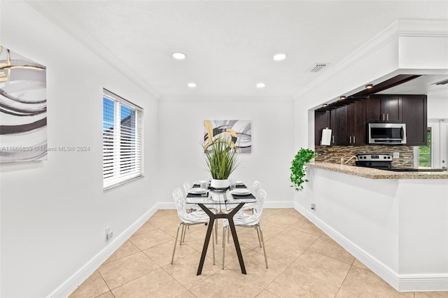 kitchen featuring dark brown cabinetry, appliances with stainless steel finishes, plenty of natural light, and crown molding