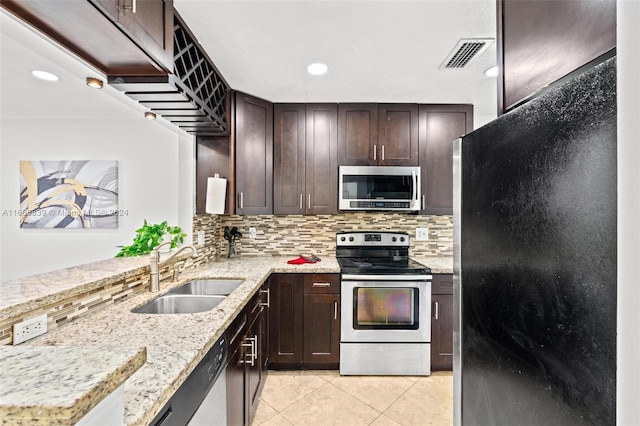 kitchen with decorative backsplash, light stone countertops, light tile patterned floors, stainless steel appliances, and sink