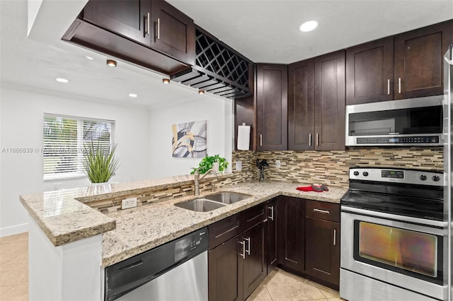 kitchen featuring appliances with stainless steel finishes, decorative backsplash, kitchen peninsula, light stone countertops, and sink