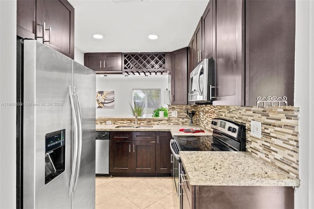 kitchen with tasteful backsplash, sink, appliances with stainless steel finishes, dark brown cabinetry, and light stone countertops