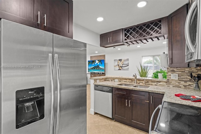 kitchen featuring light tile patterned floors, sink, tasteful backsplash, stainless steel appliances, and light stone countertops