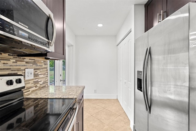 kitchen featuring appliances with stainless steel finishes, light stone counters, tasteful backsplash, light tile patterned floors, and dark brown cabinets