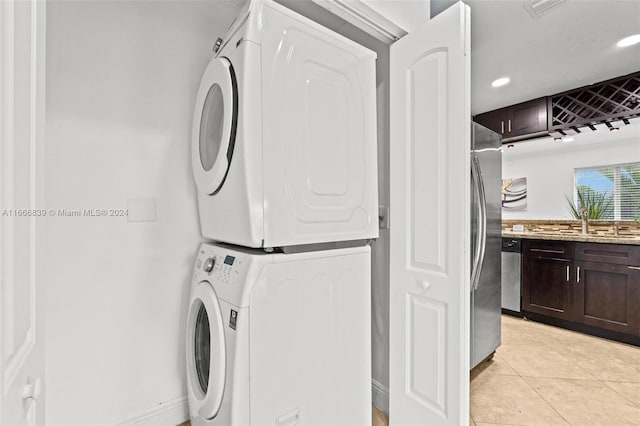 laundry area featuring stacked washer and clothes dryer and light tile patterned floors