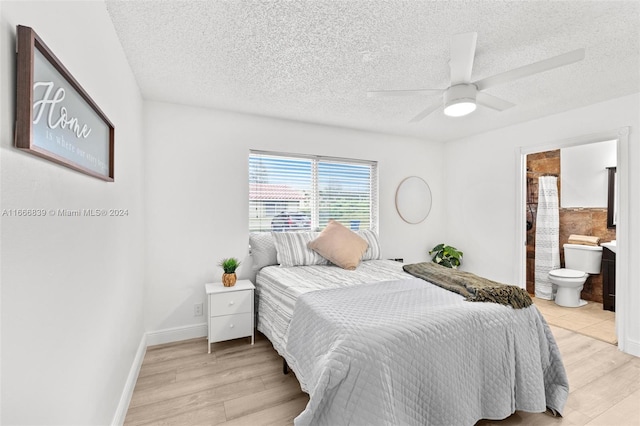 bedroom featuring ceiling fan, a textured ceiling, light wood-type flooring, and ensuite bathroom