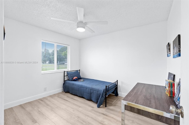 bedroom with ceiling fan, a textured ceiling, and light wood-type flooring