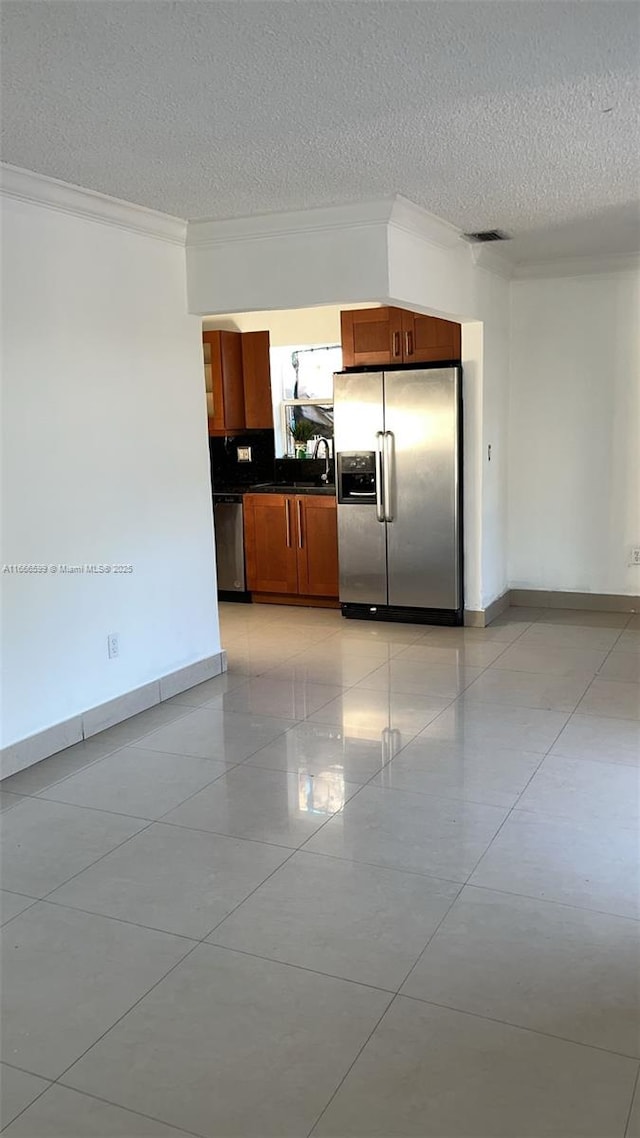 kitchen with appliances with stainless steel finishes, sink, a textured ceiling, and light tile patterned floors