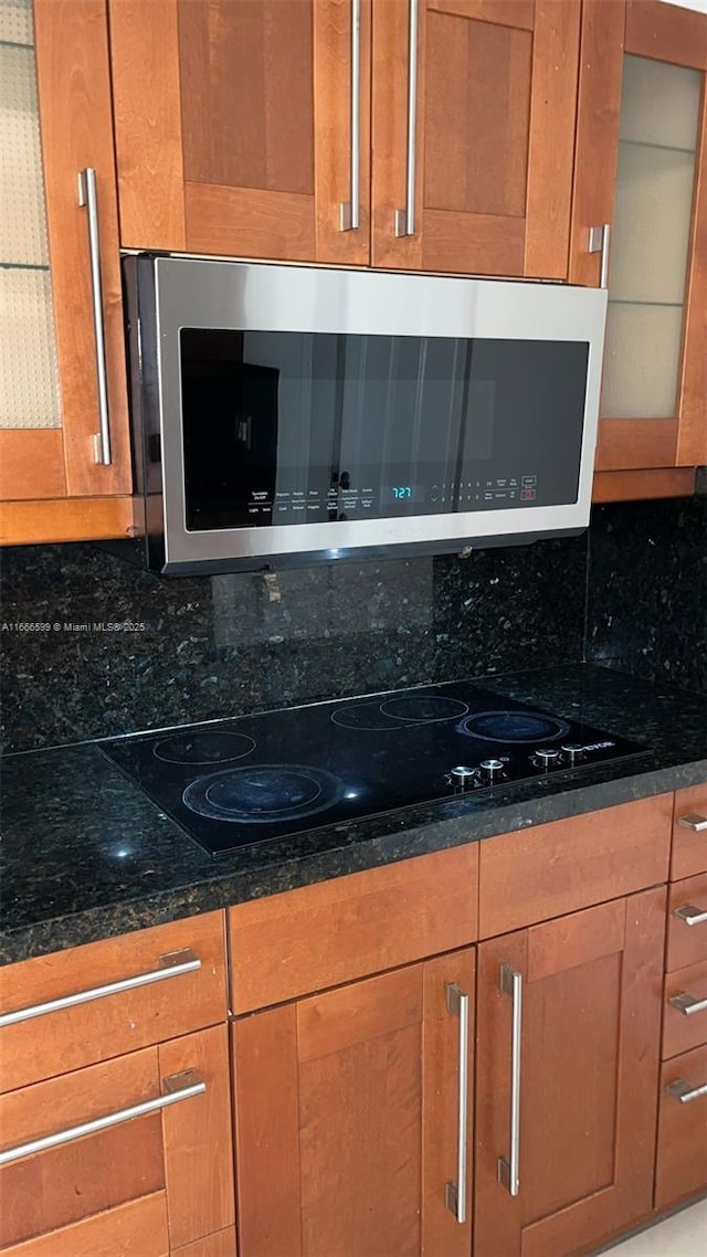 interior space featuring dark stone countertops, backsplash, and black electric cooktop