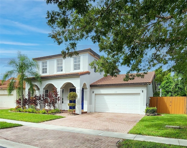 mediterranean / spanish-style house featuring a garage and a front lawn