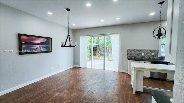 interior space with white cabinets, hanging light fixtures, dark hardwood / wood-style floors, and backsplash