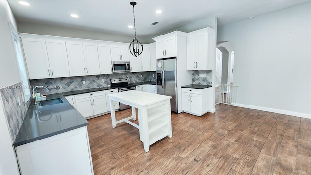 kitchen featuring white cabinetry, stainless steel appliances, sink, and decorative light fixtures