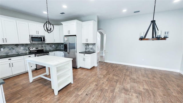 kitchen with stainless steel appliances, backsplash, white cabinetry, light wood-type flooring, and decorative light fixtures