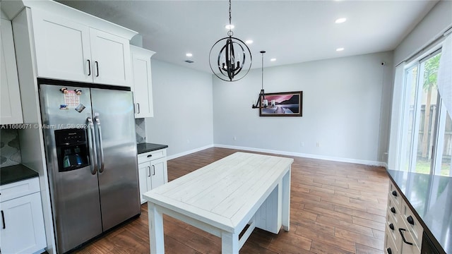 kitchen with dark hardwood / wood-style flooring, white cabinets, hanging light fixtures, tasteful backsplash, and stainless steel fridge