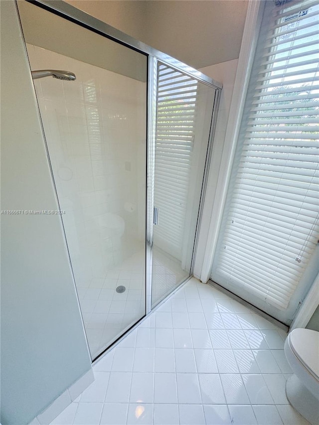 bathroom with tile patterned flooring, an enclosed shower, and toilet