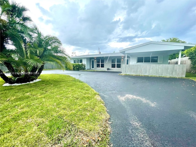 ranch-style house featuring a carport and a front lawn