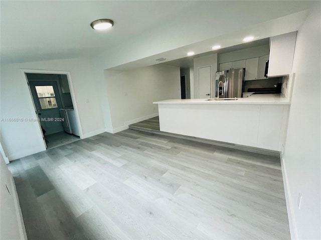 interior space with vaulted ceiling, light hardwood / wood-style floors, and washer / dryer