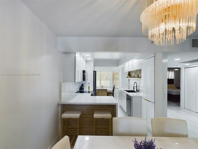 kitchen with white cabinets, sink, kitchen peninsula, dishwasher, and decorative backsplash