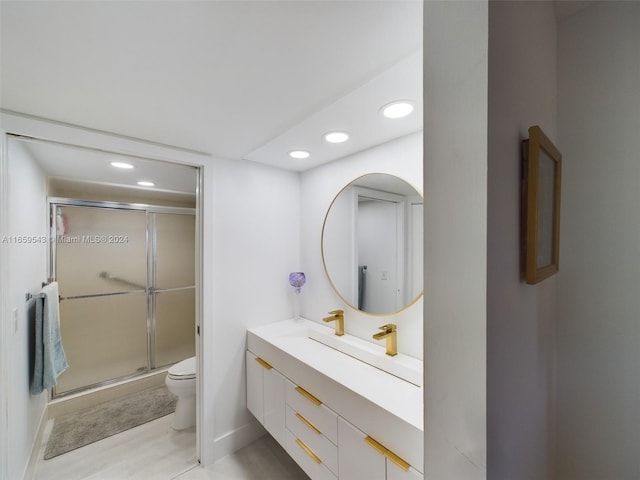 bathroom with vanity, a shower with shower door, and toilet