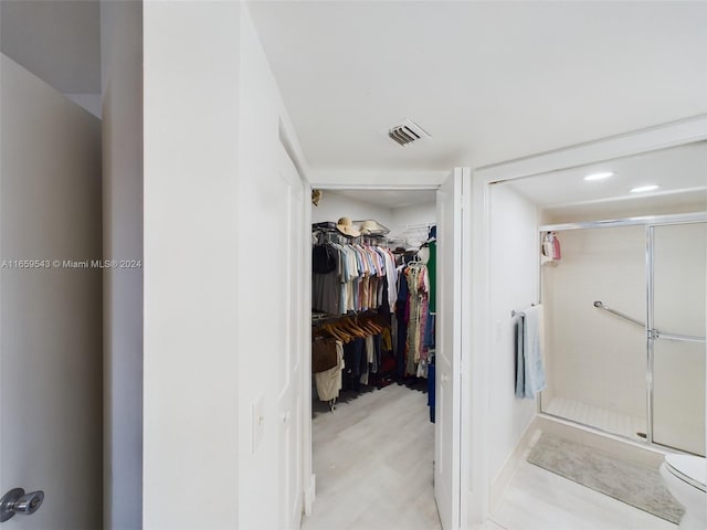 bathroom with wood-type flooring, a shower with shower door, and toilet