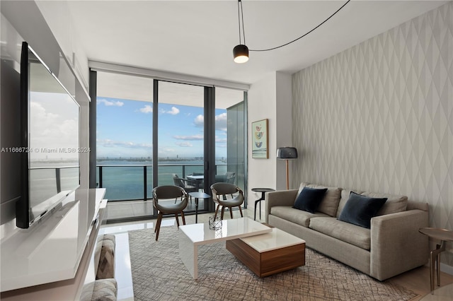 living room featuring a water view, light hardwood / wood-style floors, a wall of windows, and plenty of natural light