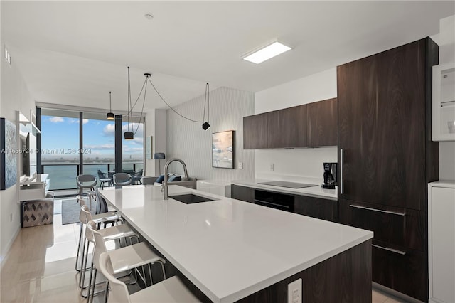 kitchen featuring a water view, a kitchen bar, a kitchen island with sink, and sink