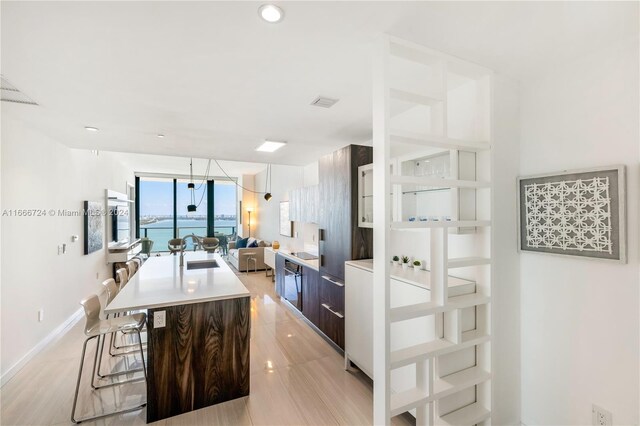 kitchen with dark brown cabinets, a kitchen breakfast bar, sink, and a center island