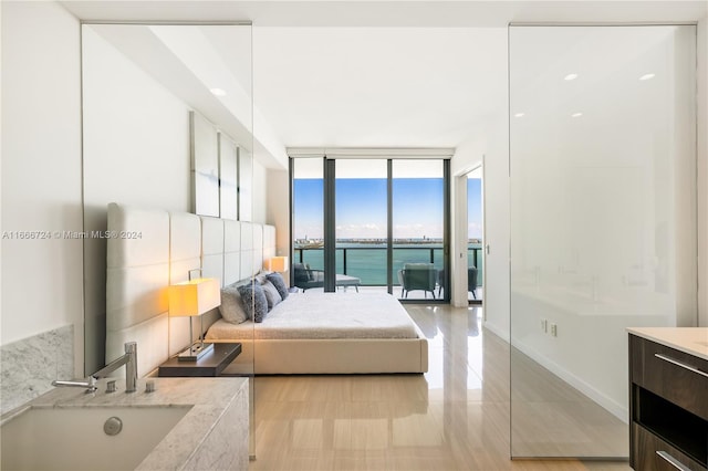 bedroom featuring a wall of windows, a water view, and access to exterior