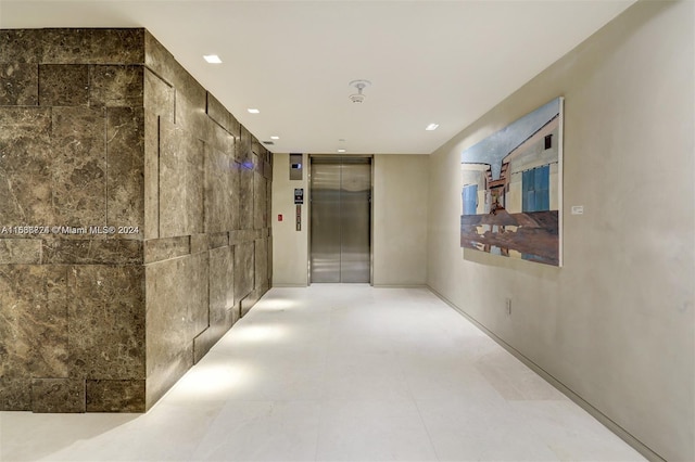 corridor with tile walls and elevator