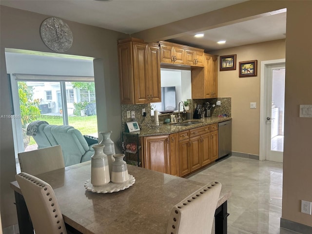 kitchen with dark stone countertops, sink, tasteful backsplash, and stainless steel dishwasher