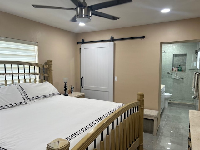 bedroom featuring a barn door, ensuite bath, and ceiling fan