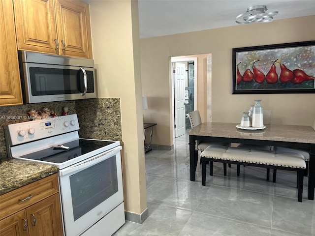 kitchen with dark stone counters, decorative backsplash, and white range with electric stovetop