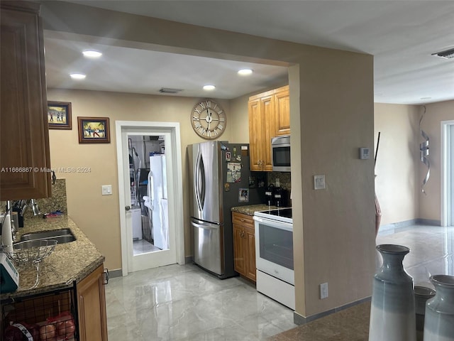 kitchen featuring appliances with stainless steel finishes, stone counters, sink, and tasteful backsplash