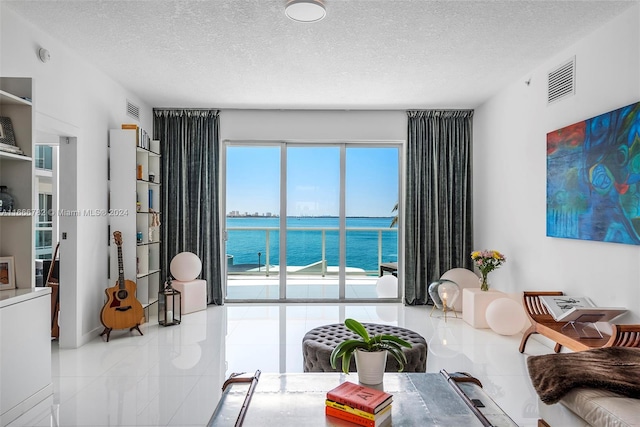 living room featuring a textured ceiling and a water view