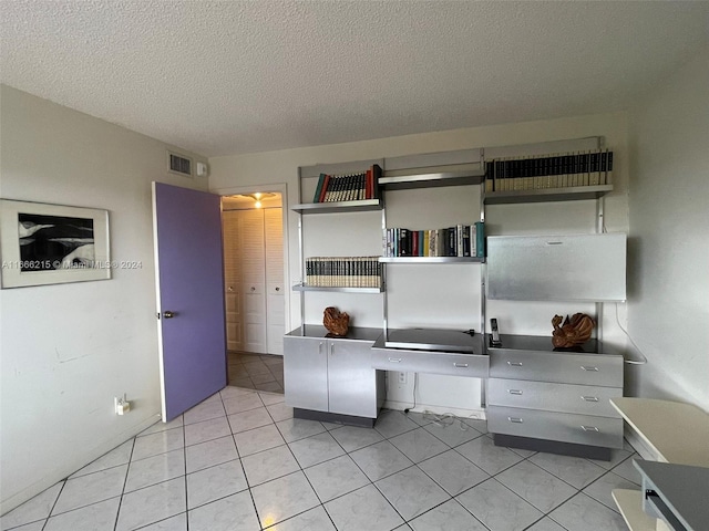 kitchen with built in desk, a textured ceiling, and light tile patterned floors