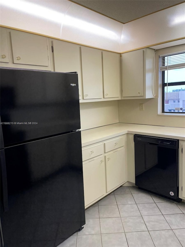 kitchen featuring black appliances, light tile patterned floors, and cream cabinetry