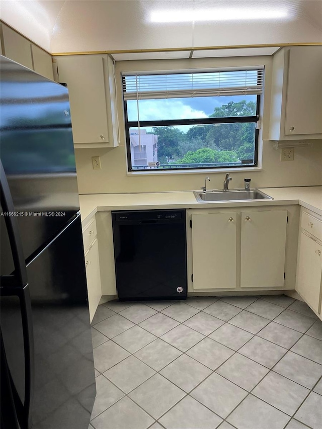 kitchen featuring cream cabinetry, stainless steel fridge, dishwasher, light tile patterned floors, and sink