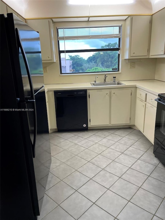 kitchen featuring black appliances, cream cabinets, sink, and light tile patterned floors