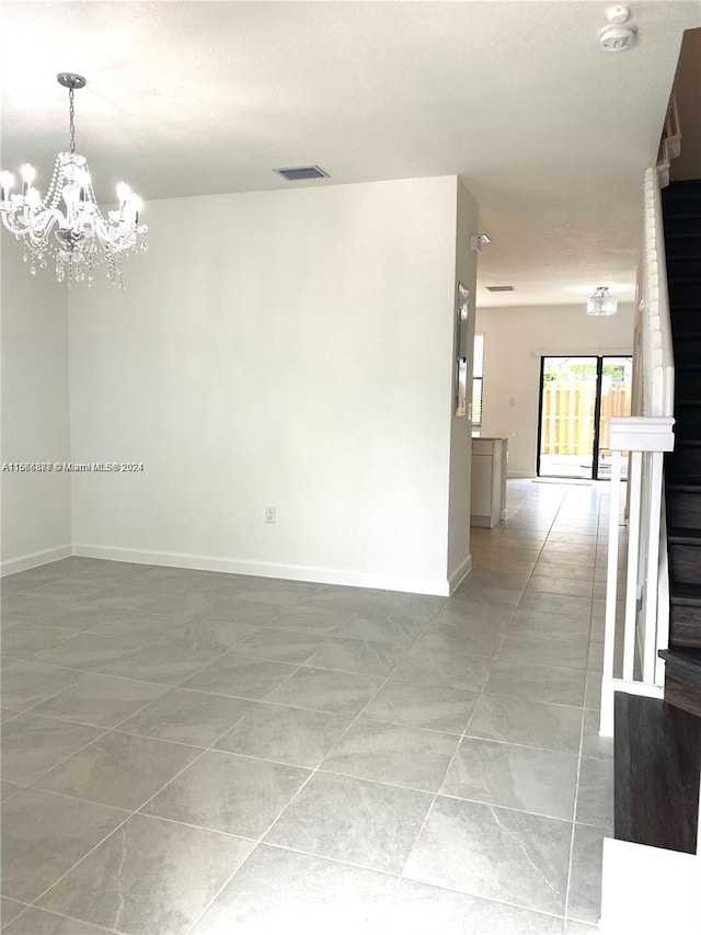 spare room featuring light tile patterned floors and a notable chandelier