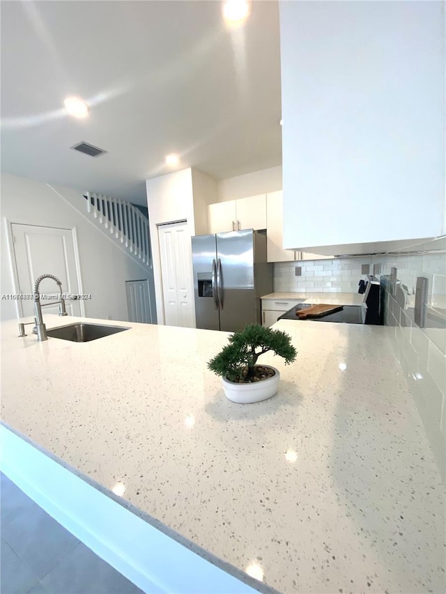 kitchen featuring appliances with stainless steel finishes, white cabinets, kitchen peninsula, light stone countertops, and sink