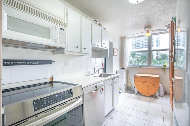 kitchen with sink, dishwasher, stove, white cabinetry, and a textured ceiling