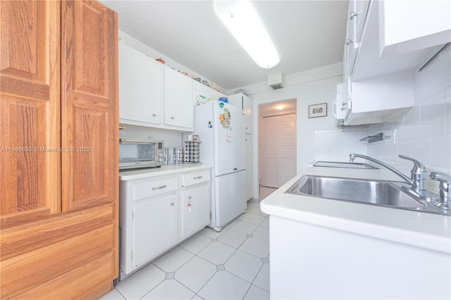 kitchen featuring white refrigerator, white cabinetry, sink, and tasteful backsplash