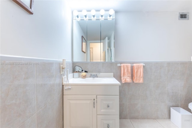 bathroom featuring tile patterned floors, visible vents, tile walls, wainscoting, and vanity