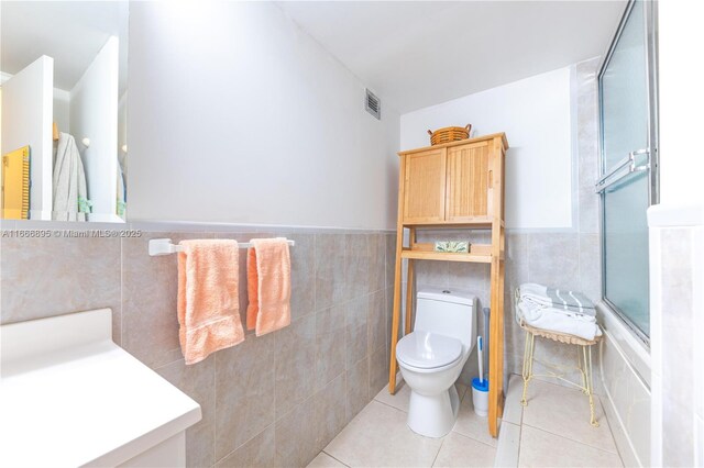 bathroom featuring toilet, tile patterned flooring, and tile walls