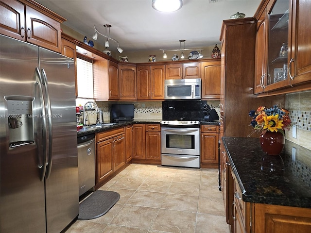 kitchen with dark stone countertops, backsplash, appliances with stainless steel finishes, and sink