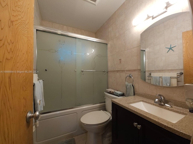 full bathroom with tile walls, combined bath / shower with glass door, backsplash, vanity, and toilet