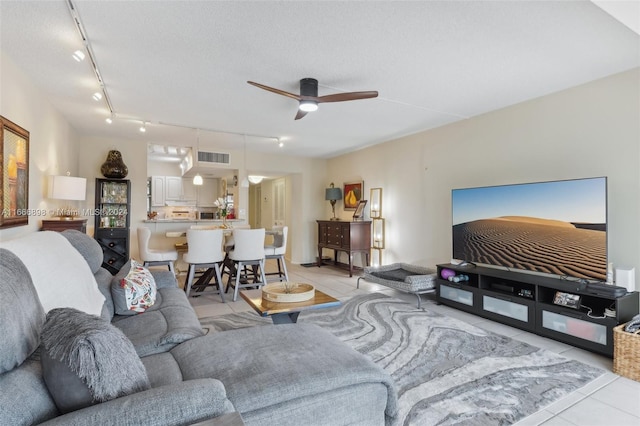 tiled living room with ceiling fan, rail lighting, and a textured ceiling