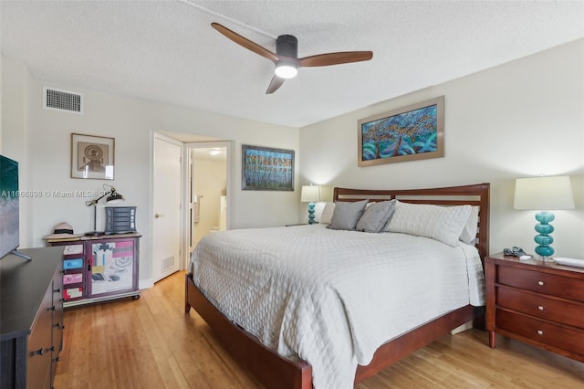 bedroom featuring ceiling fan, connected bathroom, a textured ceiling, and light wood-type flooring