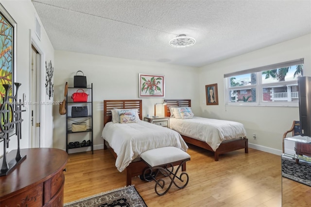 bedroom featuring a textured ceiling and light hardwood / wood-style flooring