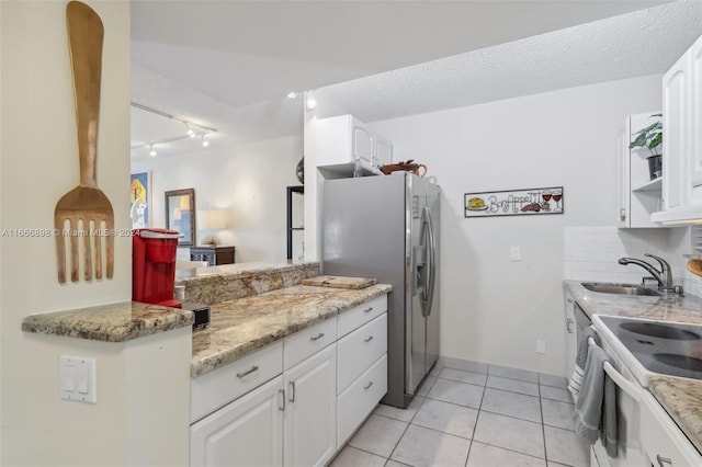 kitchen with stainless steel refrigerator with ice dispenser, sink, white cabinets, and light stone counters