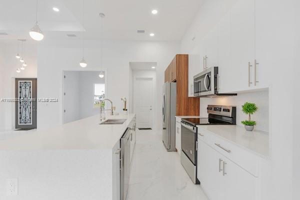 kitchen with white cabinetry, sink, stainless steel appliances, and decorative light fixtures